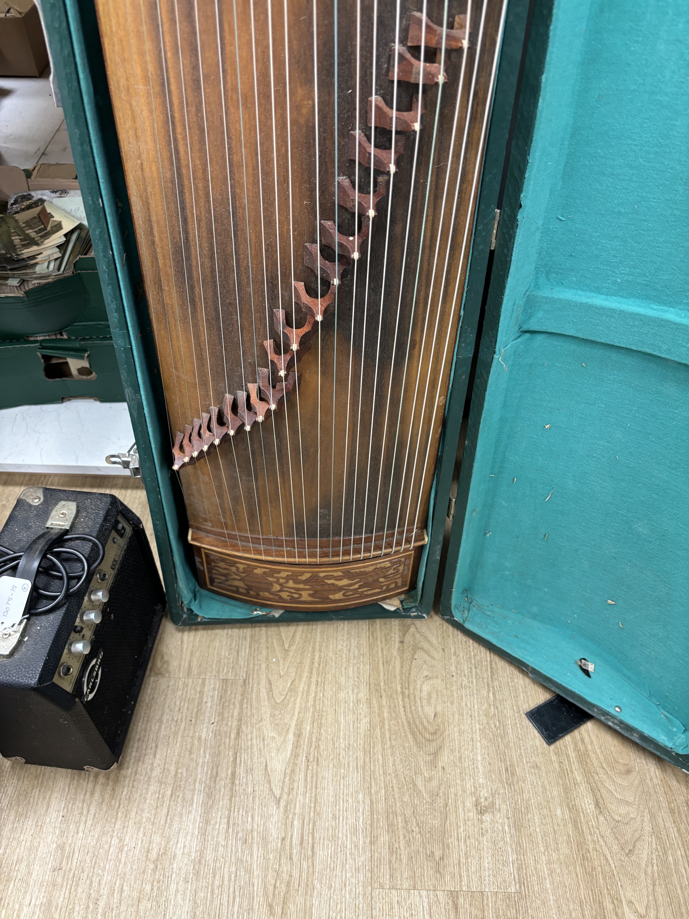 A cased Chinese Guzheng zither harp, hardwood body with blind fretwork decorative panel of birds and trees, with 21 strings, in fitted hard case, 163cm long